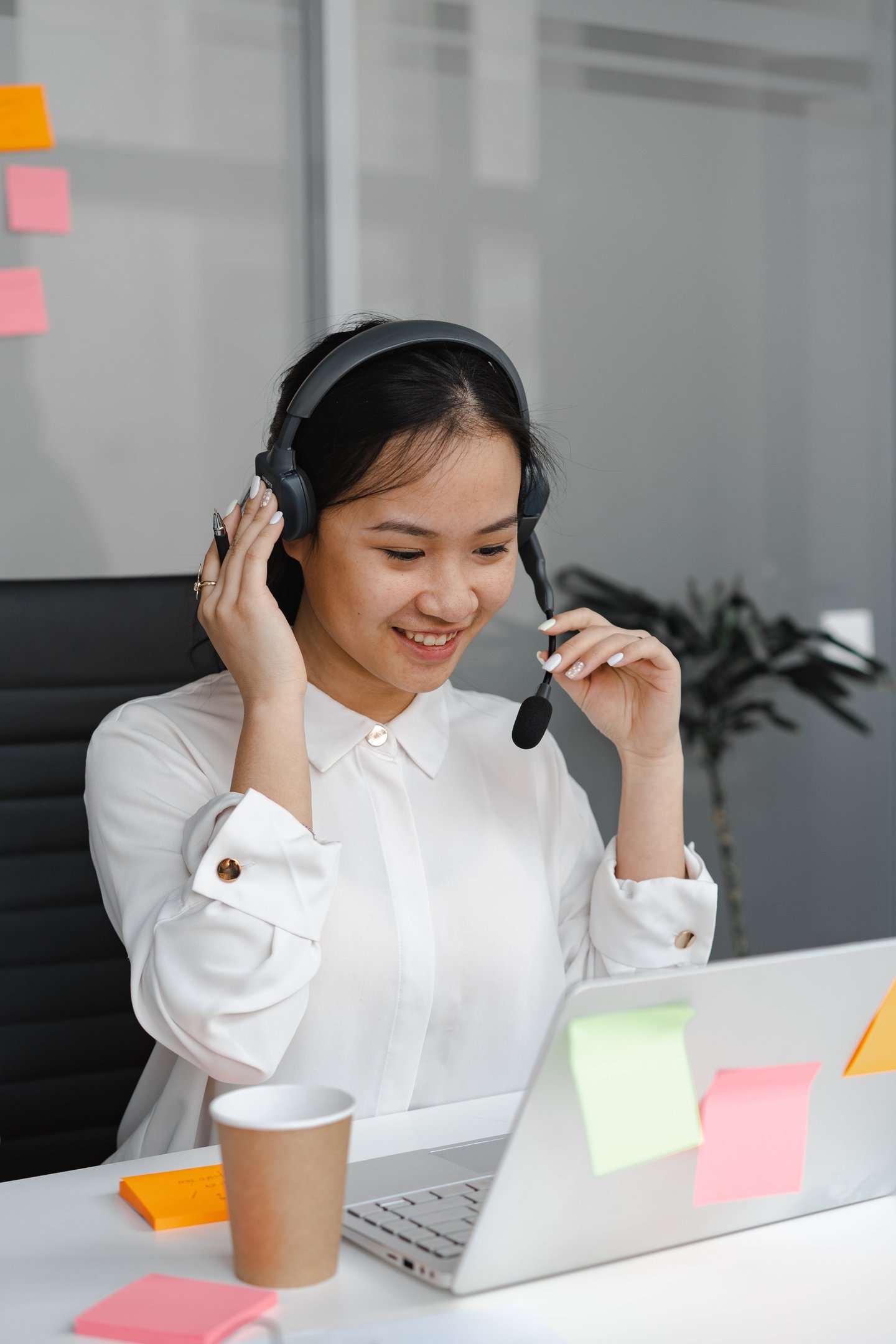 a woman in a white shirt and headphones on a laptop